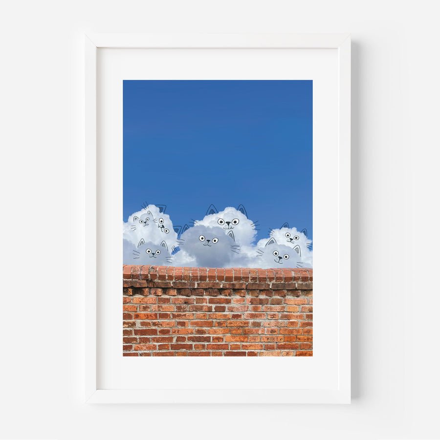 Framed artwork of fluffy white cats on a brick wall with blue sky background